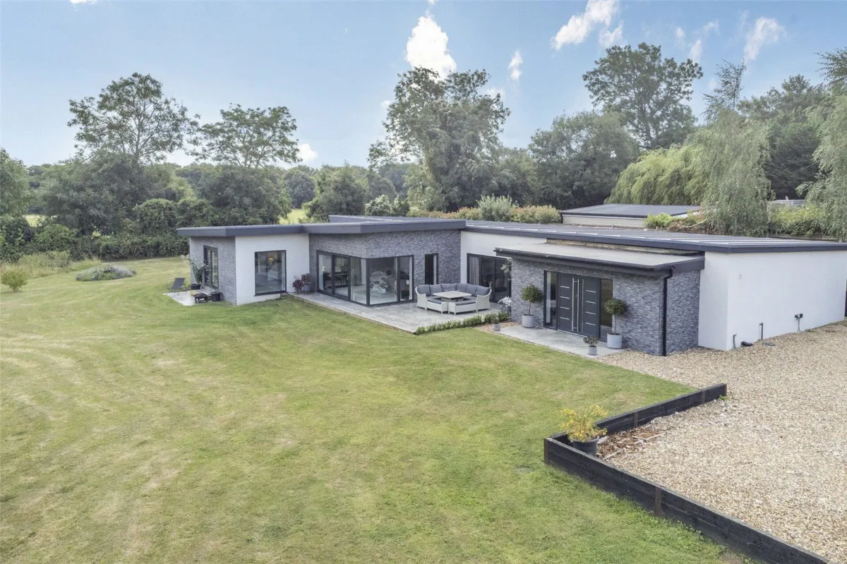 A modern flat-roofed single-storey house with large glazing and a lawn on Church Road, Hartley
