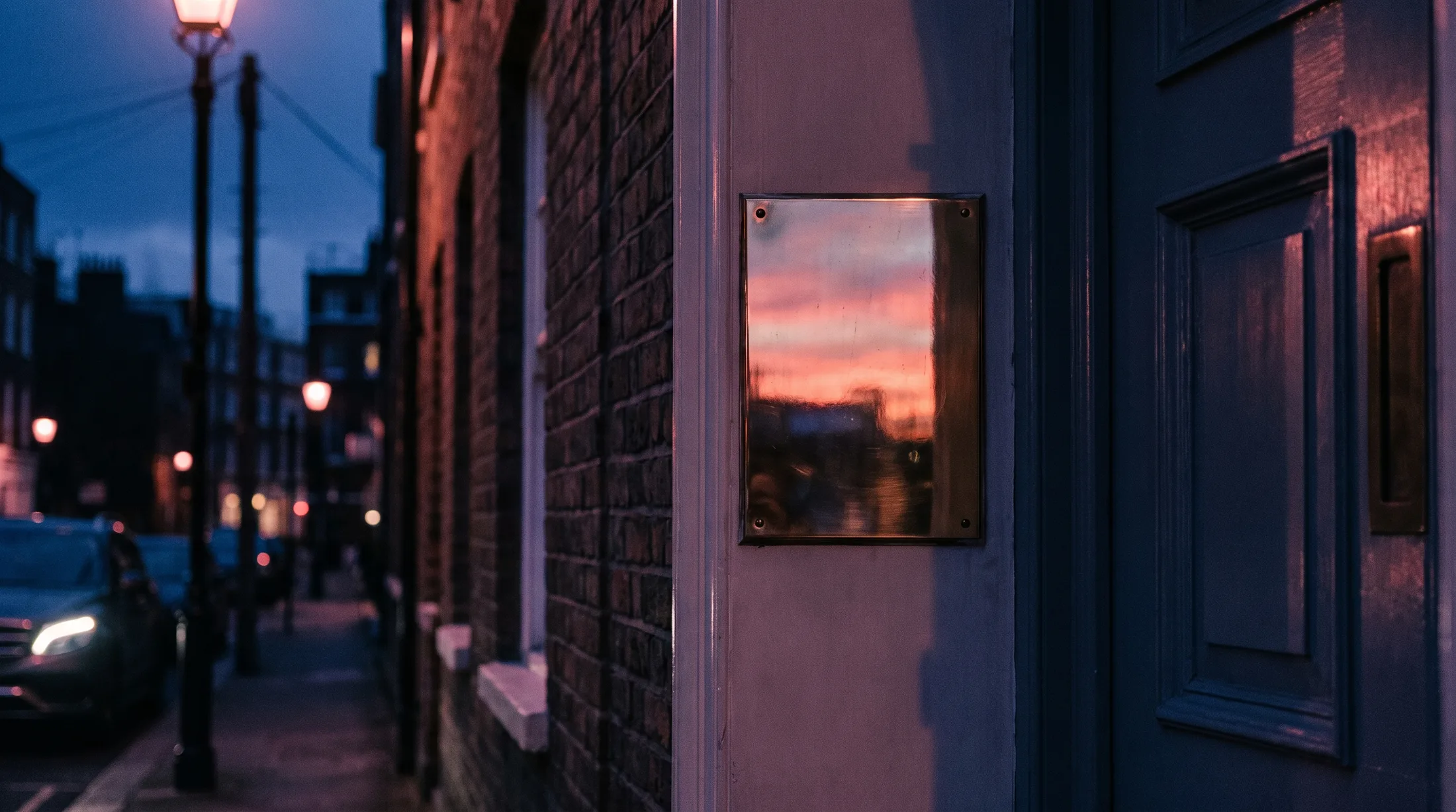 A polished blank brass plaque beside a period London front door at pink dusk — the space where a firm's earned reputation goes